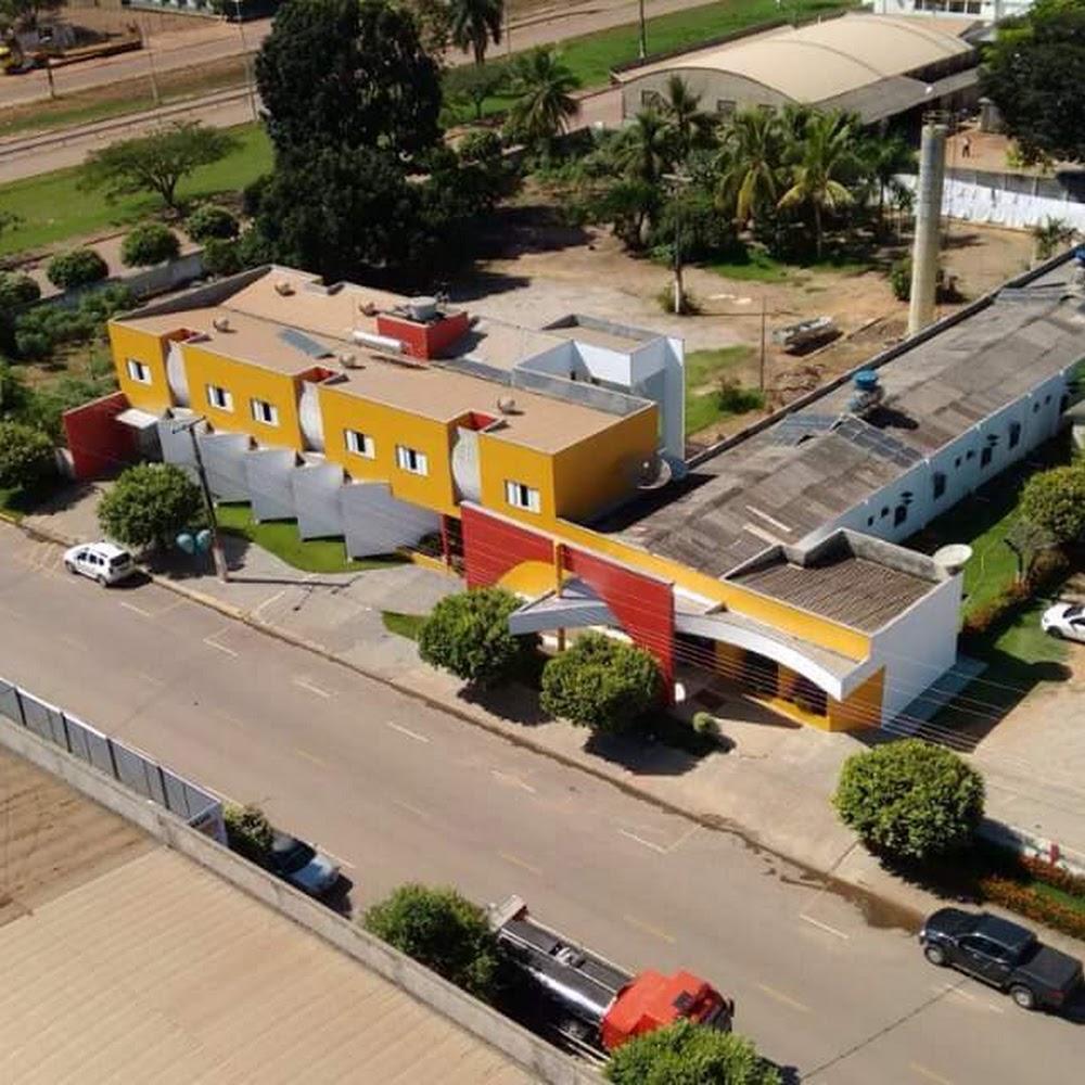 Vista aérea do Hotel Flor da Mata, com fachada amarela e detalhes em vermelho, no centro de Guarantã do Norte