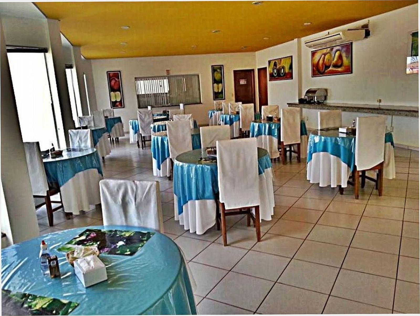 Salão do café da manhã do Hotel Flor da Mata com mesas postas e cadeiras com capa branca