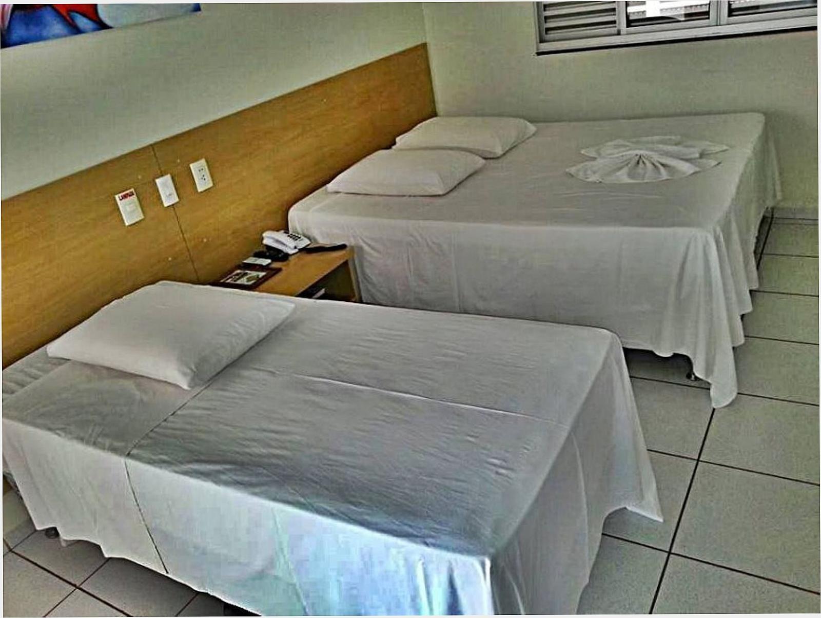 Quarto com duas camas de solteiro, ar-condicionado e piso claro