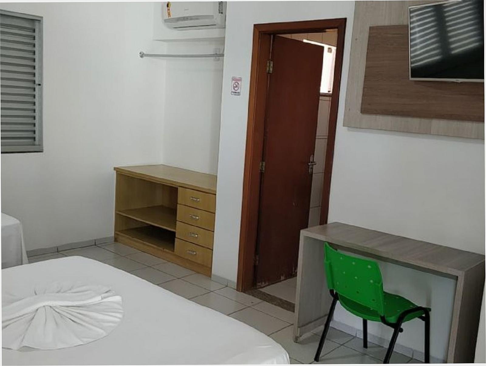 Quarto com TV na parede, armário de madeira e escrivaninha
